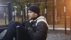 Mladý muž cvičí břišní svaly venku v zimním parku