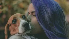 Žena líbající hnědého a bílého psa