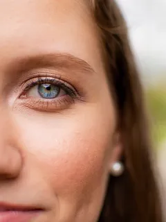 extrémní makro modrých očí ženy se stříbrným piercingem v nose