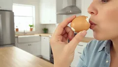 Žena fouká do vajíčka v kuchyni při vyklepávání obsahu vejce.