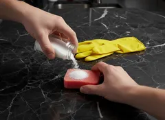 Soda na houbi, úklid kuchyně, žluté rukavice na černé mramorové desce