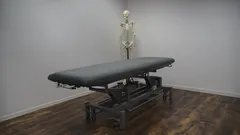 Černý rám postele na hnědé dřevěné parketové podlaze