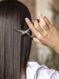 Žena stříhá vlasy nůžkami, detailní záběr