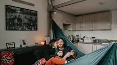Žena v černé bundě leží na modrém houpacím síti