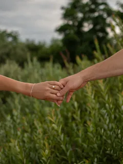 Nevěsta a ženich držící se za ruce na poli