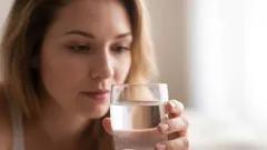 Žena drží sklenici vody a připravuje se napít, zdravý životní styl, hydratace