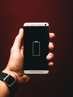 Osoba drží smartphone s nízkou úrovní baterie